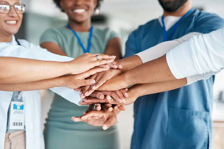 healthcare professionals in a team formation of hands in a circle